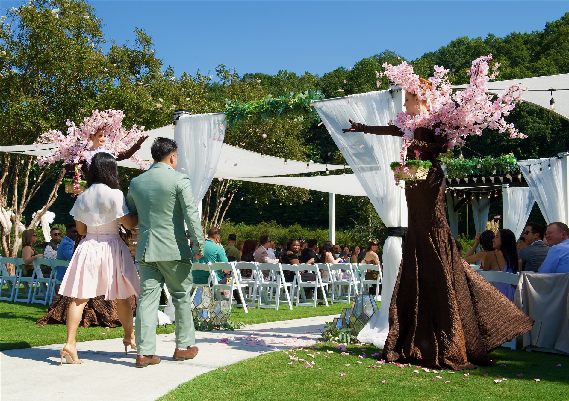 Cherry blossom stilt performers welcoming guests at an outdoor celebration